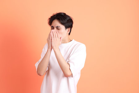 The Adult east Asian man with braces standing on the pink or orange background.の写真素材