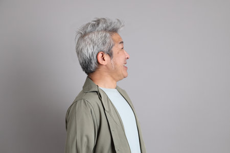 The 40s Asian man with smart casual clothes standing on the grey background.の写真素材