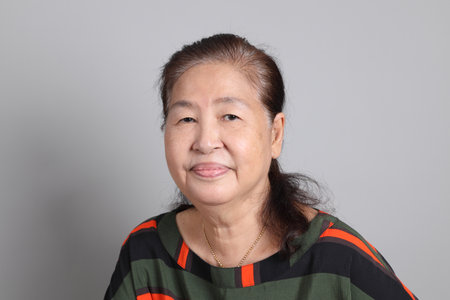 The 70s Chinese senior woman with casual clothes standing on the grey background.の写真素材