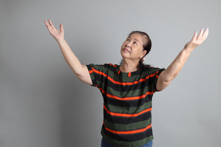 The 70s Chinese senior woman with casual clothes standing on the grey background.の写真素材