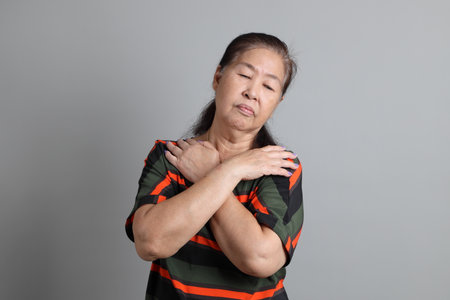 The 70s Chinese senior woman with casual clothes standing on the grey background.の写真素材