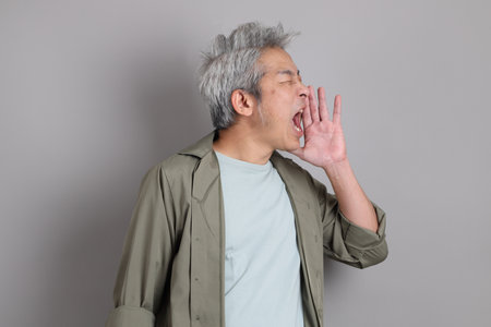 The 40s Asian man with smart casual clothes standing on the grey background.の写真素材
