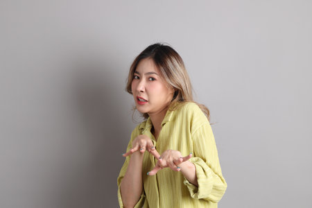 The Asian woman in casual dressed standing on the grey background.の写真素材