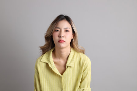 The Asian woman in casual dressed standing on the grey background.
