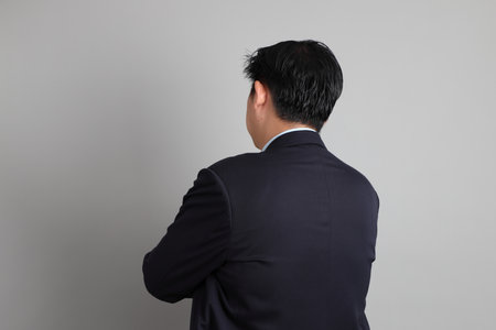 The Asian Businessman with formal dressed with gesture of standing on the gray background.