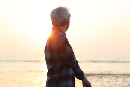 The silhouette of senior Asian man walking along the beach in the evening timeの写真素材
