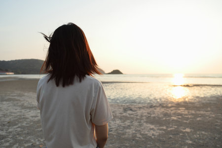The Asian woman relaxing along the beach under the sunset time.の写真素材
