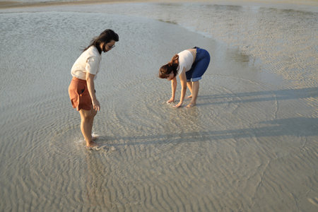 Two Asian friends spending time together on the beach during the evening in the summer season.