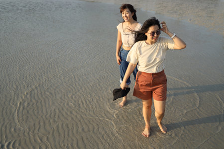 Two Asian friends spending time together on the beach during the evening in the summer season.