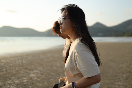 Two Asian friends spending time together on the beach during the evening in the summer season.の写真素材