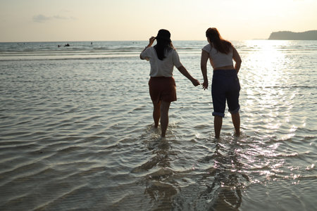 Two Asian friends spending time together on the beach during the evening in the summer season.の写真素材