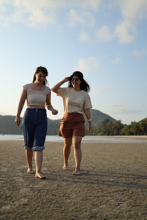 Two Asian friends spending time together on the beach during the evening in the summer season.の写真素材