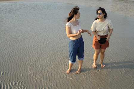 Two Asian friends spending time together on the beach during the evening in the summer season.の写真素材
