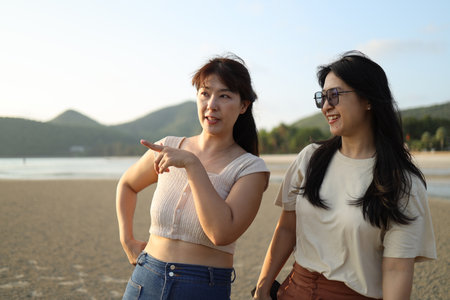 Two Asian friends spending time together on the beach during the evening in the summer season.の写真素材