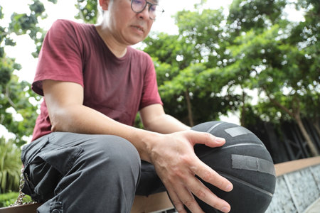 Cheerful active senior man playing basketball on the basketball street court with gusture of holding the ball.の写真素材