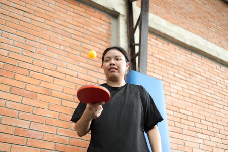 Asian young woman  is playing table tennis while holding a ball and a racket in his hands in public table tennis clubの写真素材