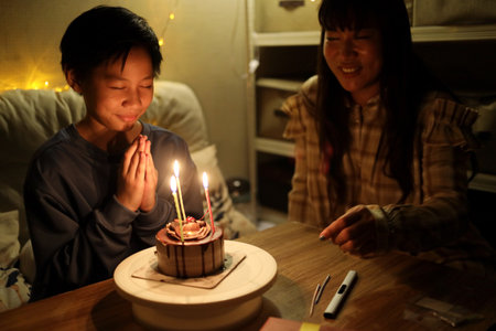 The single Asian mother celebrating herson birthday in the small living room.の写真素材
