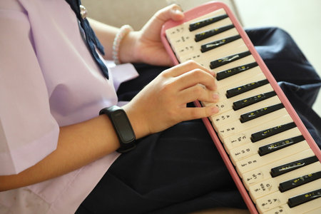 The East Asian kid practicing melodion after the school.の写真素材