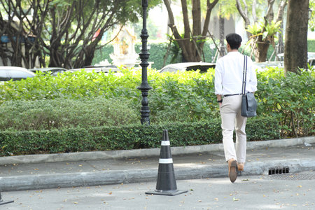 The 40-year-old Asian businessman walking in the parking lot during the daytime.の写真素材