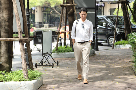 The 40-year-old Asian businessman walking in the parking lot during the daytime.の写真素材
