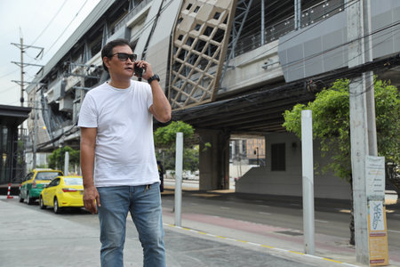 The Southeast Asian person using smart phone walking on the footpath.