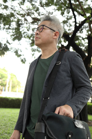 A senior Asian businessman walking in the park.