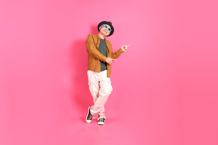 A senior East Asian man stands against a hot pink background, wearing a colorful shirt.の写真素材