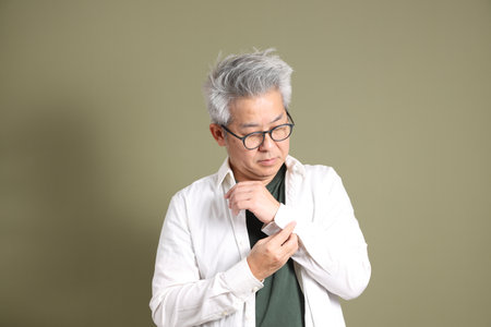 A half-body portrait of an East Asian businessman, isolated against a deep green background, taken in a studio.の写真素材