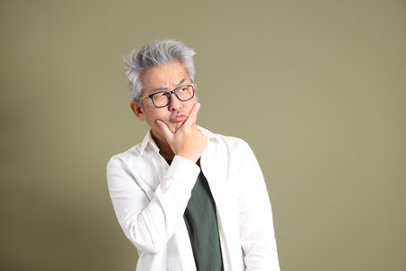 A half-body portrait of an East Asian businessman, isolated against a deep green background, taken in a studio.の写真素材