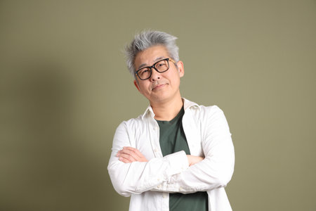 A half-body portrait of an East Asian businessman, isolated against a deep green background, taken in a studio.の写真素材