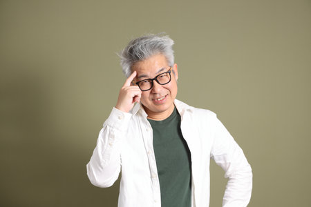 A half-body portrait of an East Asian businessman, isolated against a deep green background, taken in a studio.の写真素材