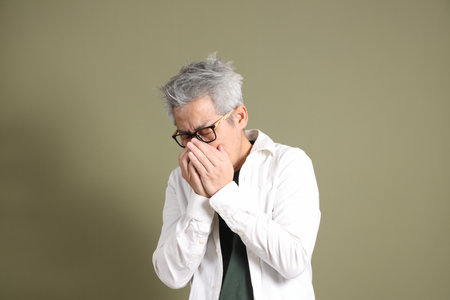 A half-body portrait of an East Asian businessman, isolated against a deep green background, taken in a studio.の写真素材