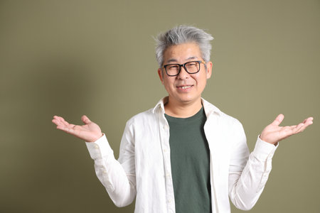 A half-body portrait of an East Asian businessman, isolated against a deep green background, taken in a studio.の写真素材