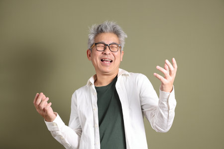 A half-body portrait of an East Asian businessman, isolated against a deep green background, taken in a studio.の写真素材