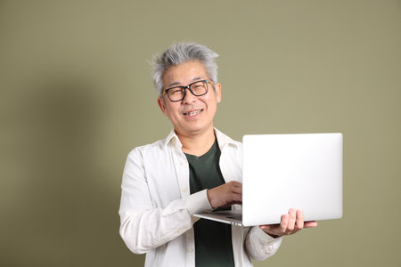 A half-body portrait of an East Asian businessman, isolated against a deep green background, taken in a studio.の写真素材