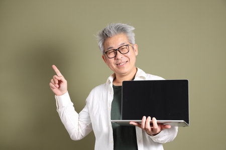A half-body portrait of an East Asian businessman, isolated against a deep green background, taken in a studio.の写真素材