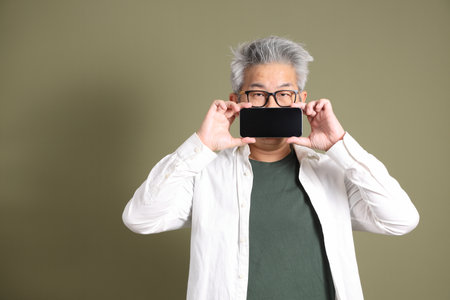 A half-body portrait of an East Asian businessman, isolated against a deep green background, taken in a studio.の写真素材
