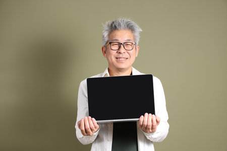 A half-body portrait of an East Asian businessman, isolated against a deep green background, taken in a studio.の写真素材
