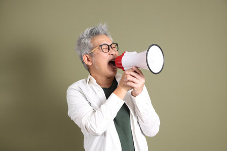 A half-body portrait of an East Asian businessman, isolated against a deep green background, taken in a studio.の写真素材