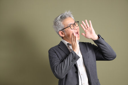 A half-body portrait of an East Asian businessman, isolated against a deep green background, taken in a studio.の写真素材