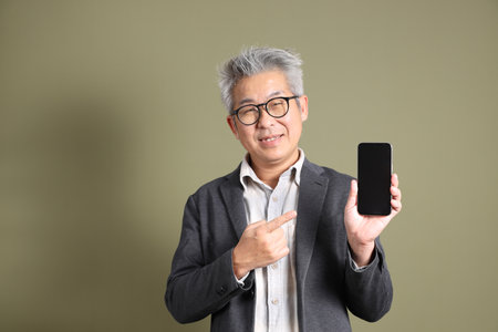 A half-body portrait of an East Asian businessman, isolated against a deep green background, taken in a studio.の写真素材