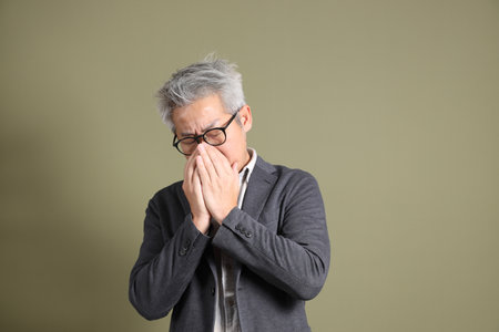 A half-body portrait of an East Asian businessman, isolated against a deep green background, taken in a studio.の写真素材