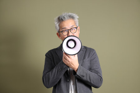 A half-body portrait of an East Asian businessman, isolated against a deep green background, taken in a studio.の写真素材