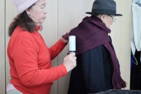 An East Asian elderly couple helping each other dress in winter clothes to go outside