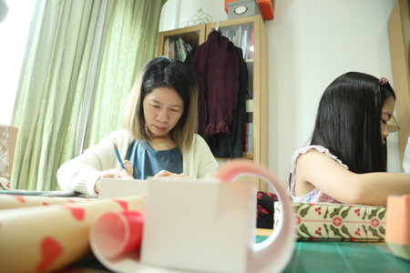 East Asian parents helping their daughter and teaching her how to wrap a present for the upcoming New Year's Day.の写真素材