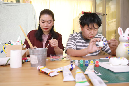 The East Asian single mother and her son are painting eggs for the upcoming Easter.の写真素材