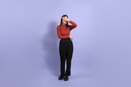 The young Southeast Asian woman in casual clothes, standing against a purple background.の写真素材