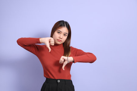 The young Southeast Asian woman in casual clothes, standing against a purple background.
