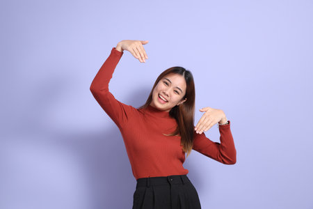 The young Southeast Asian woman in casual clothes, standing against a purple background.の写真素材