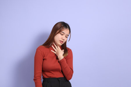 The young Southeast Asian woman in casual clothes, standing against a purple background.の写真素材